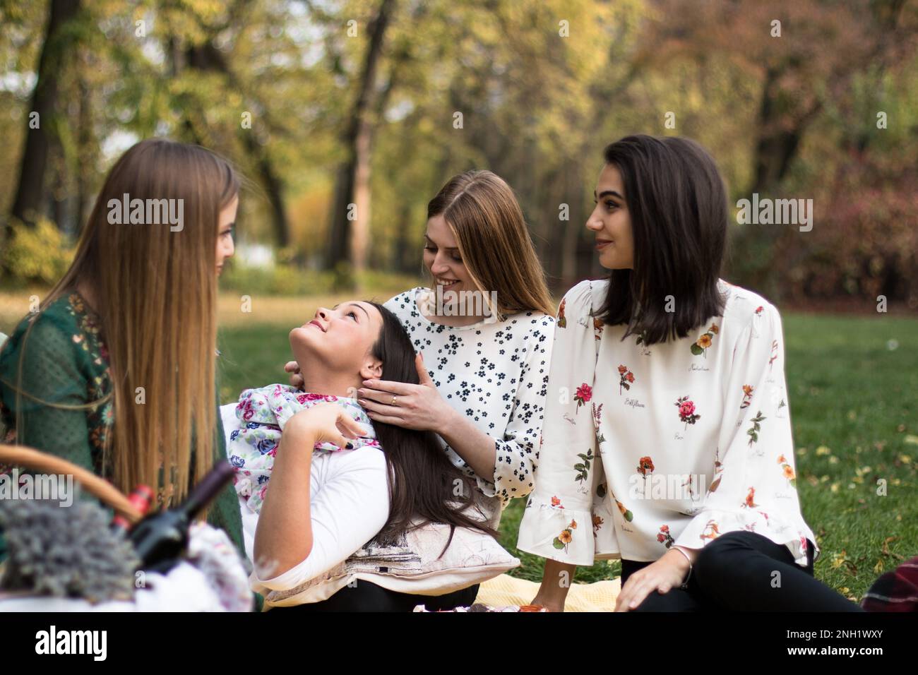Group of four women on a fun fall picnic in the park, having a good time. Stock Photo