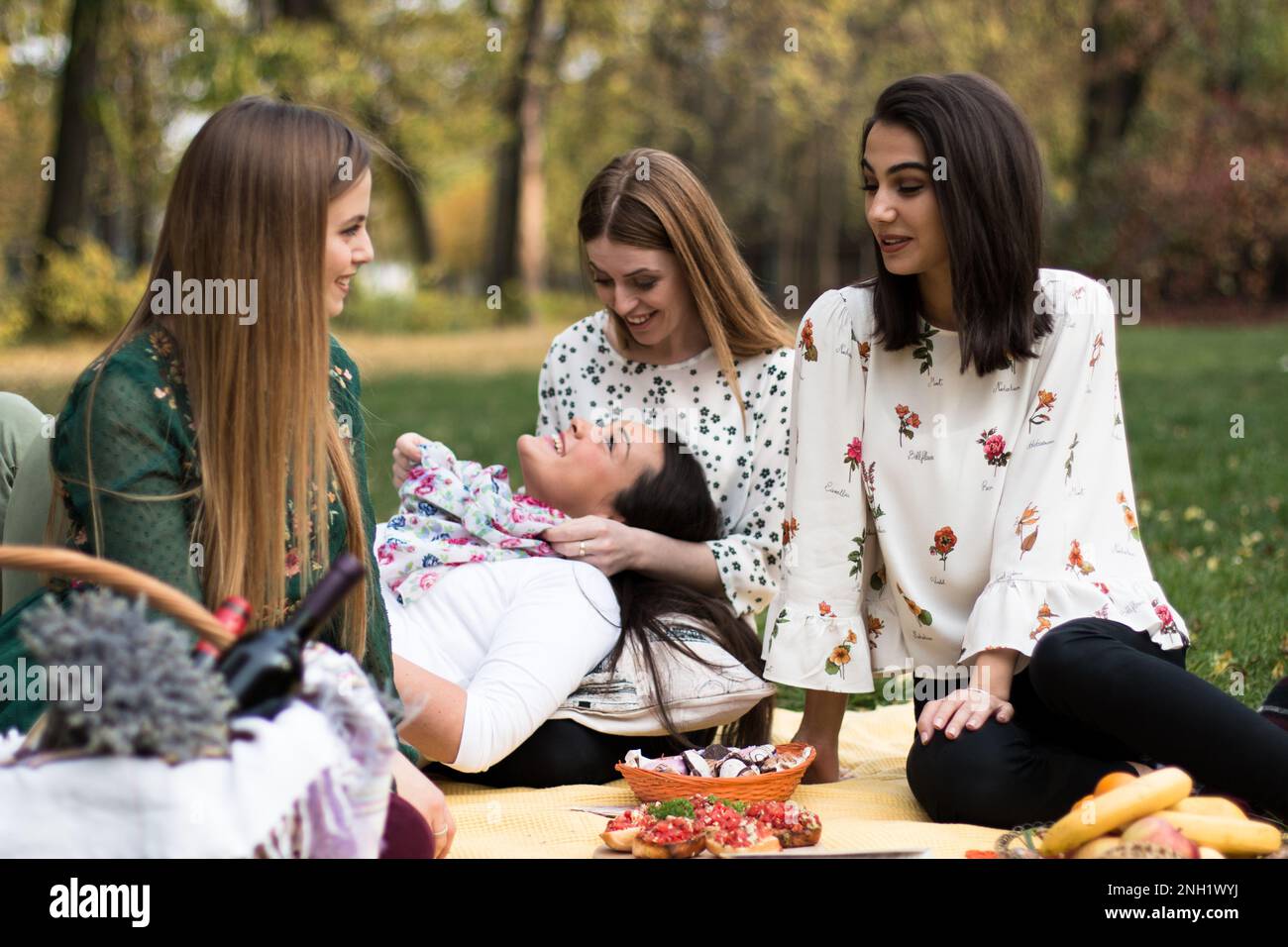 Group of four women on a fun fall picnic in the park, having a good time. Stock Photo