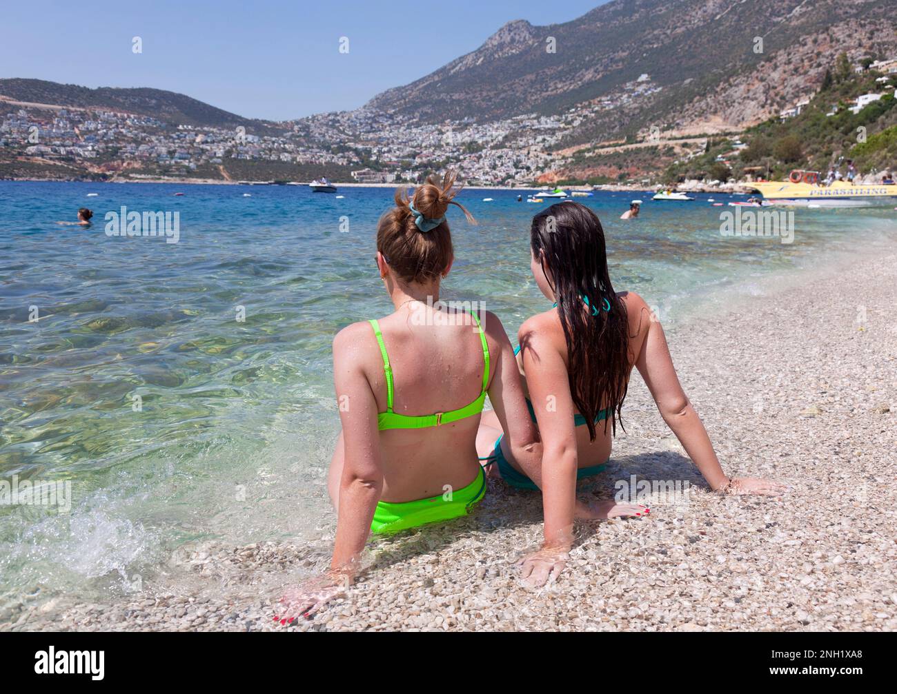 Young women ( model released ) enjoying the clear sea waters and beach at the Kalkan Beach park in Kalkan, Turkey. July 2022 Stock Photo