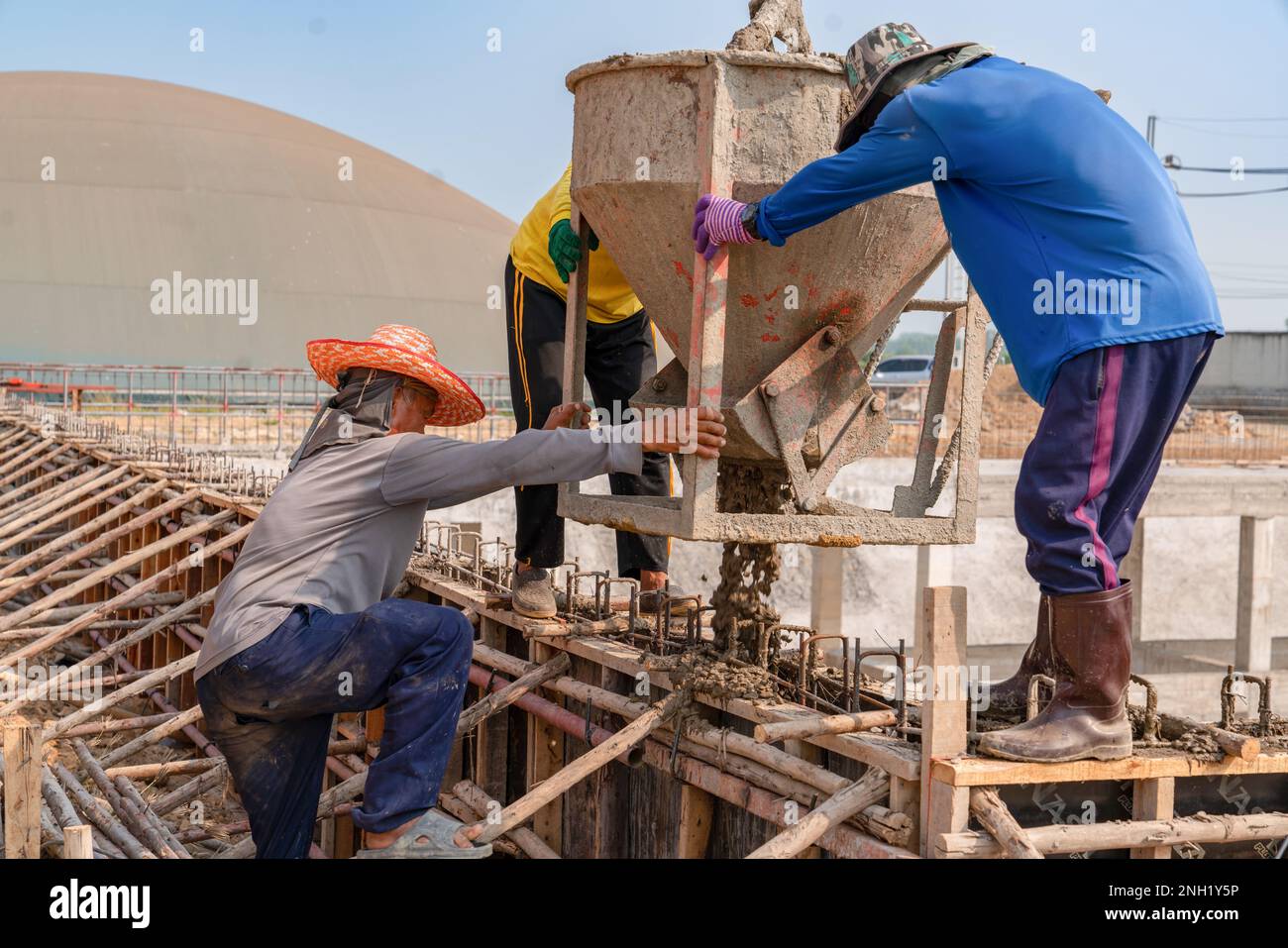 construction workers pour raw concrete using from bucket into the