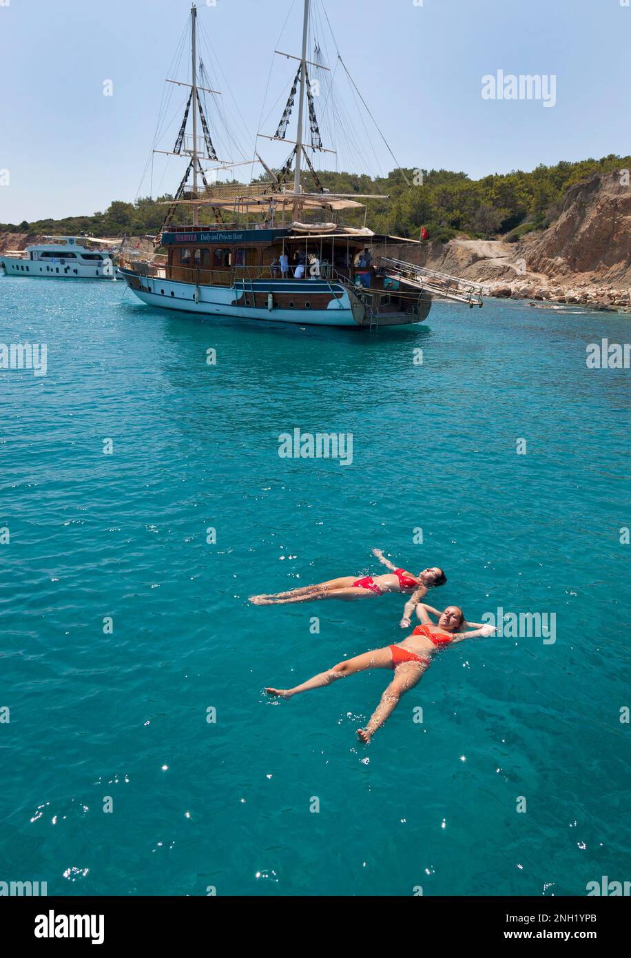 Young women ( model released ) wearing bikini swimwear enjoy a day out aboard a private chartered Gulet sailing in Kalkan bay near to  Kalkan, Turkey. Stock Photo