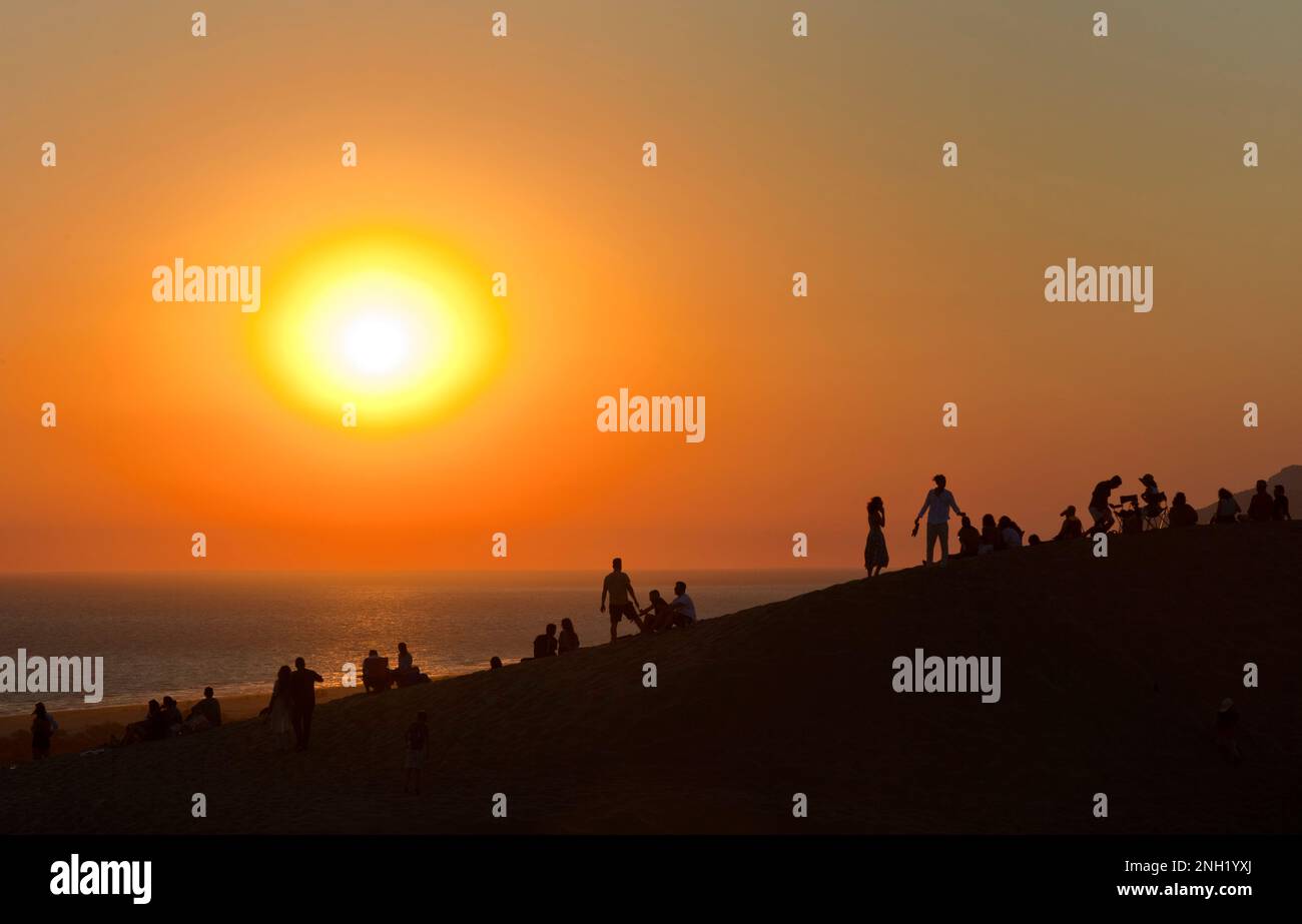 Tourists watch the sunset on Patara beach near the ancient Lycian city of Patara in Turkey. July 2022 Stock Photo