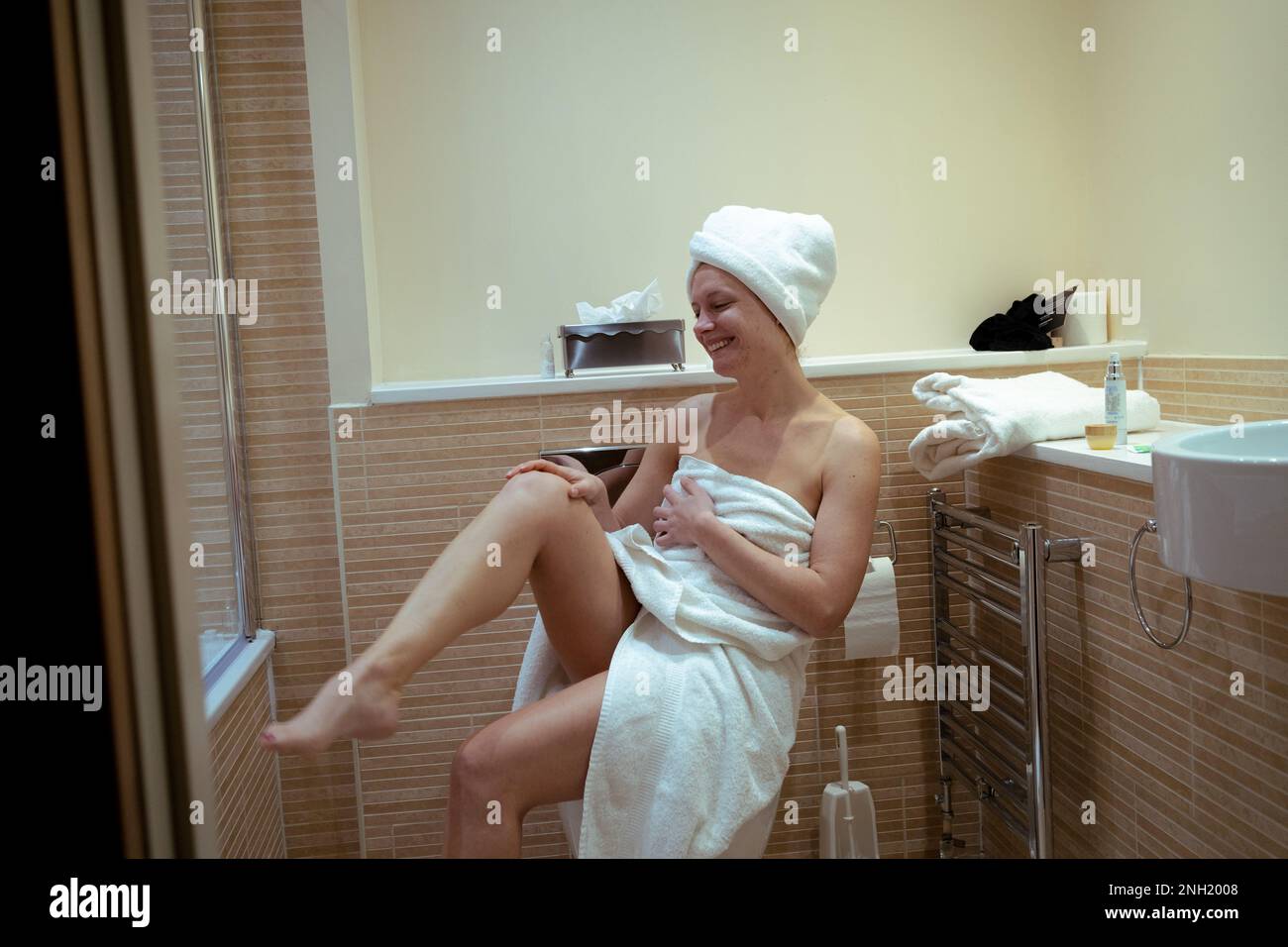 https://c8.alamy.com/comp/2NH2008/smiling-young-woman-raises-a-leg-in-bathroom-after-shower-beauty-routine-at-home-2NH2008.jpg