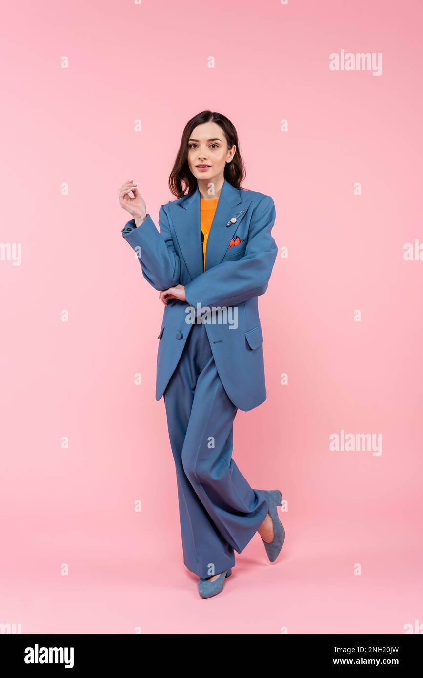 full length of young brunette woman in blue pantsuit standing on pink,stock image Stock Photo