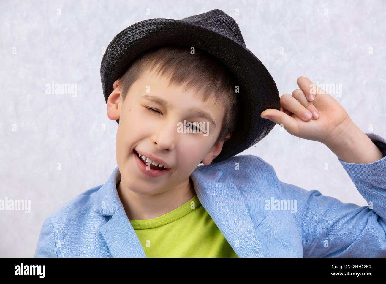 Portrait of a handsome cheerful winking boy in a hat. Stock Photo