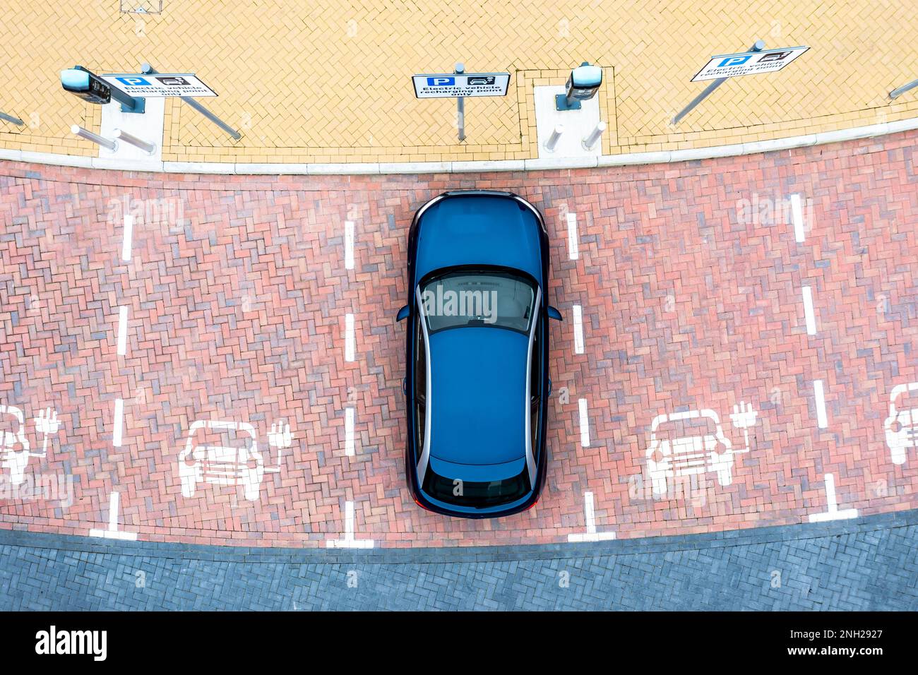 Aerial view directly above an electric vehicle charging station with parking spaces and road markings denoting charging bays Stock Photo