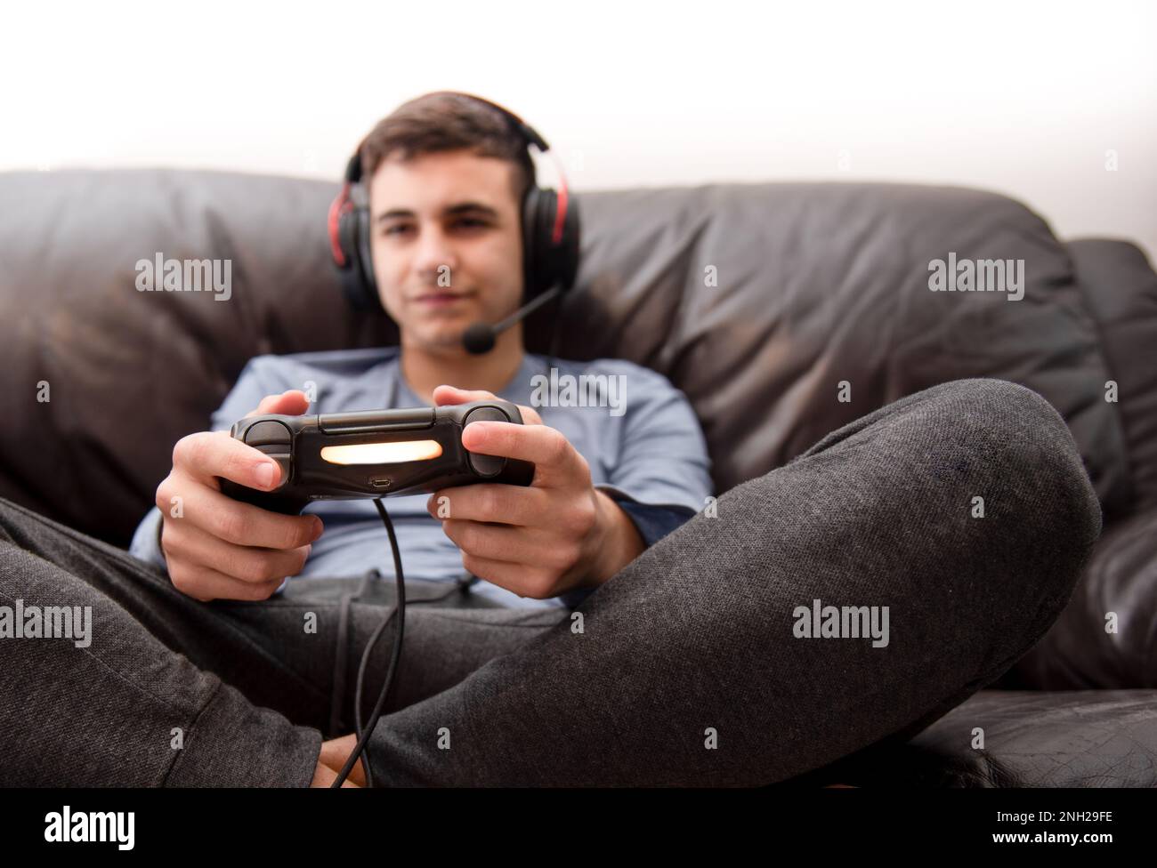 teenager playing video games at home sitting on couch Stock Photo
