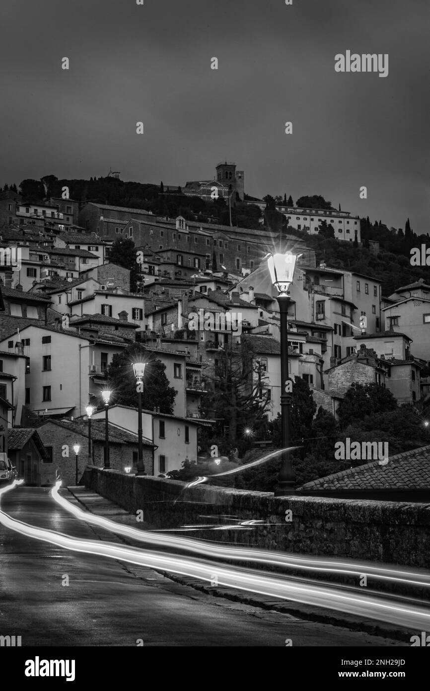 Tuscany, Italy. Night long exposure black and white photograph with car trails, star light effect view of old town. Warm tones and mood. Street travel Stock Photo
