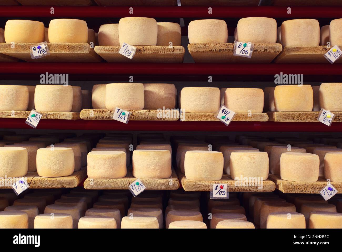 Parmesan Cheese Rows On Wooden Shelves With Production Dates In Farmer