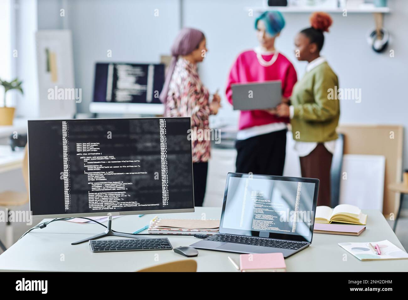 Close up of two computer screen with code lines and blurred creative team in background, copy space Stock Photo