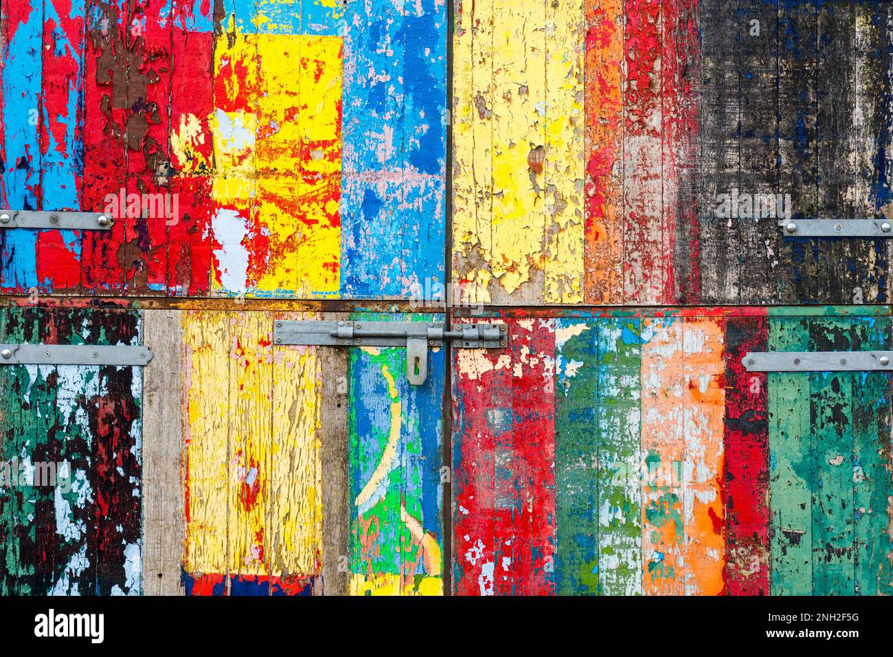 Colourfully painted garage or shed door with texture and decay of old paint. Stock Photo