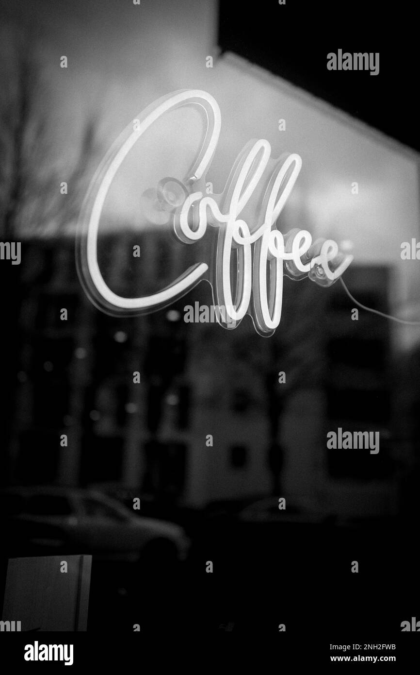 Neon Coffee sign in a cafe window with reflection of buildings Stock Photo