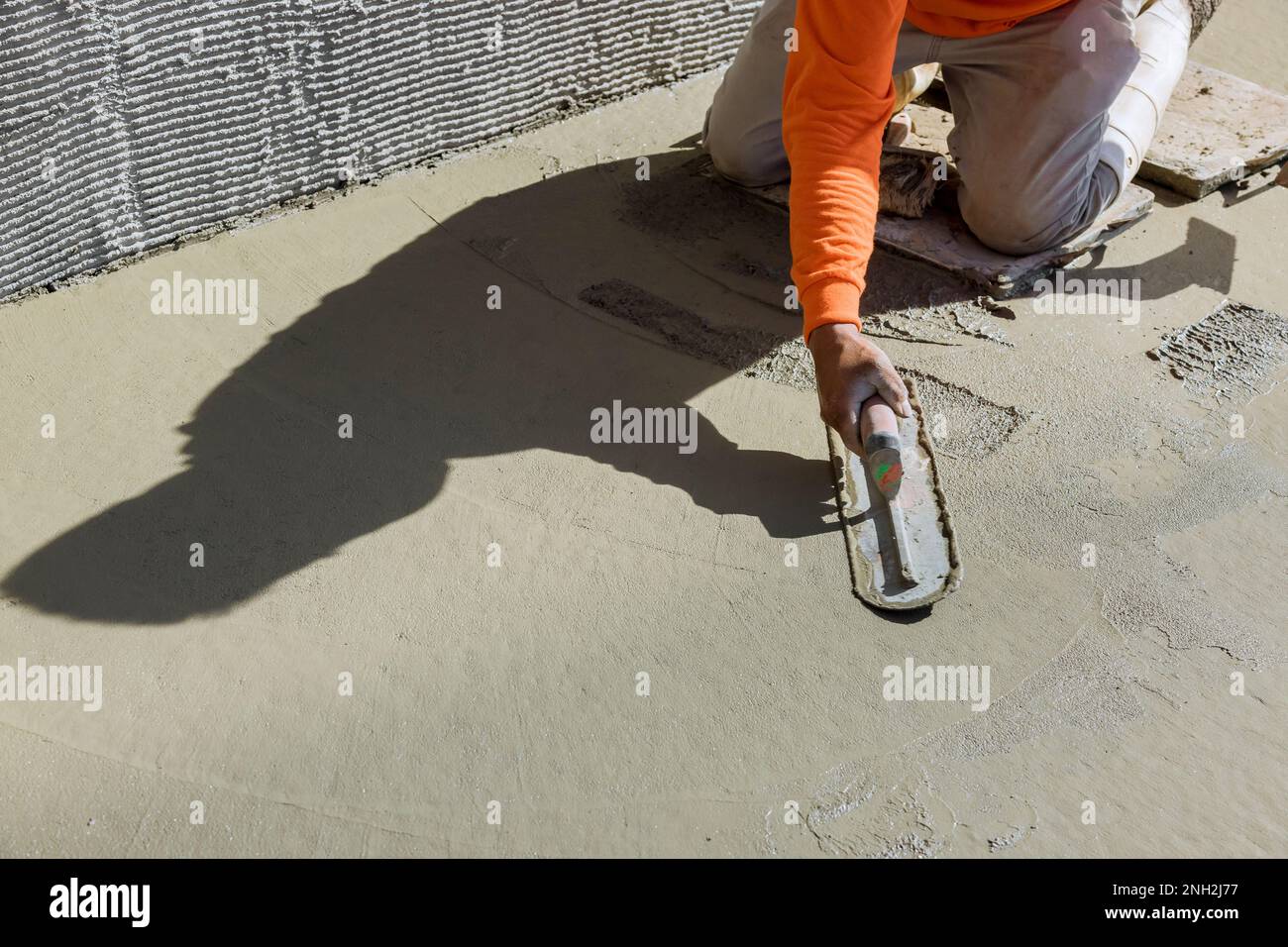 Plastering wet cement concrete floors with use of trowel after concrete