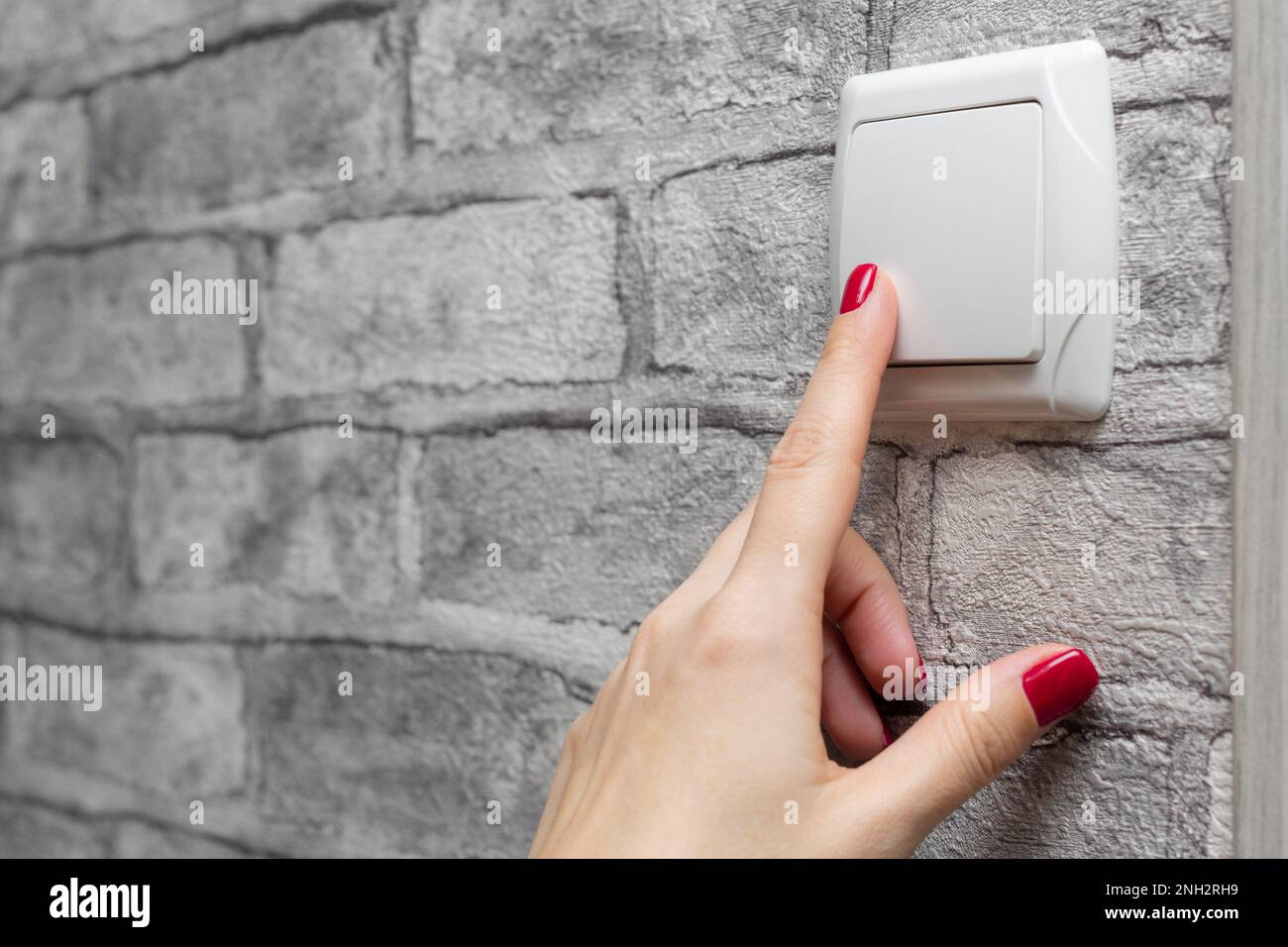 female hand presses the fingers on the light switch. woman turns on the