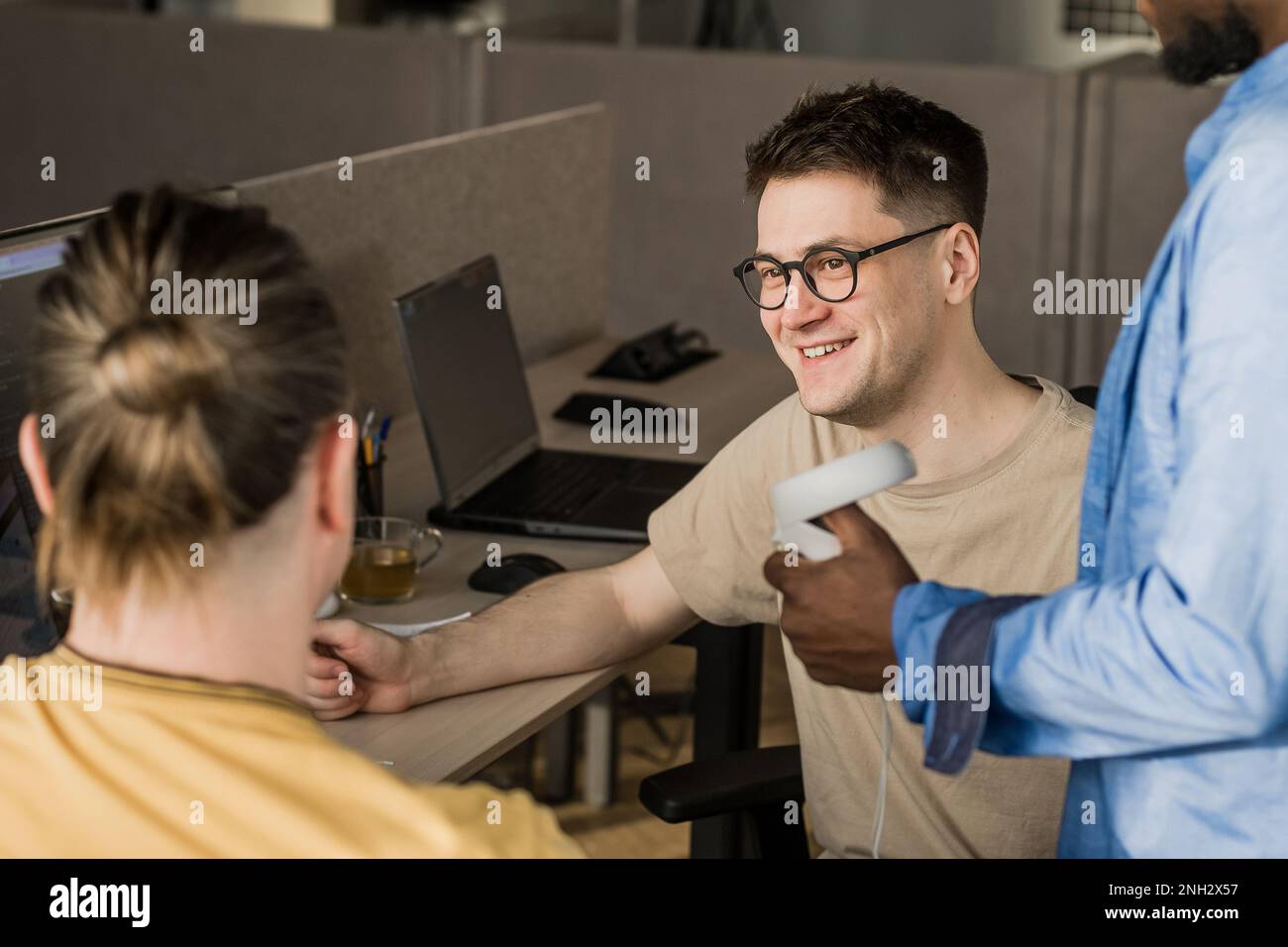 IT Development Team Working on VR Project. Man wearing VR headset, playing and touching something in the virtual world. Diverse men programmers using Stock Photo