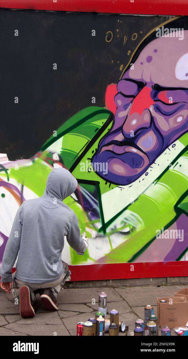 Graffiti show in Bacon St London E2. Artist working on building site hording part of weekend long project. Stock Photo