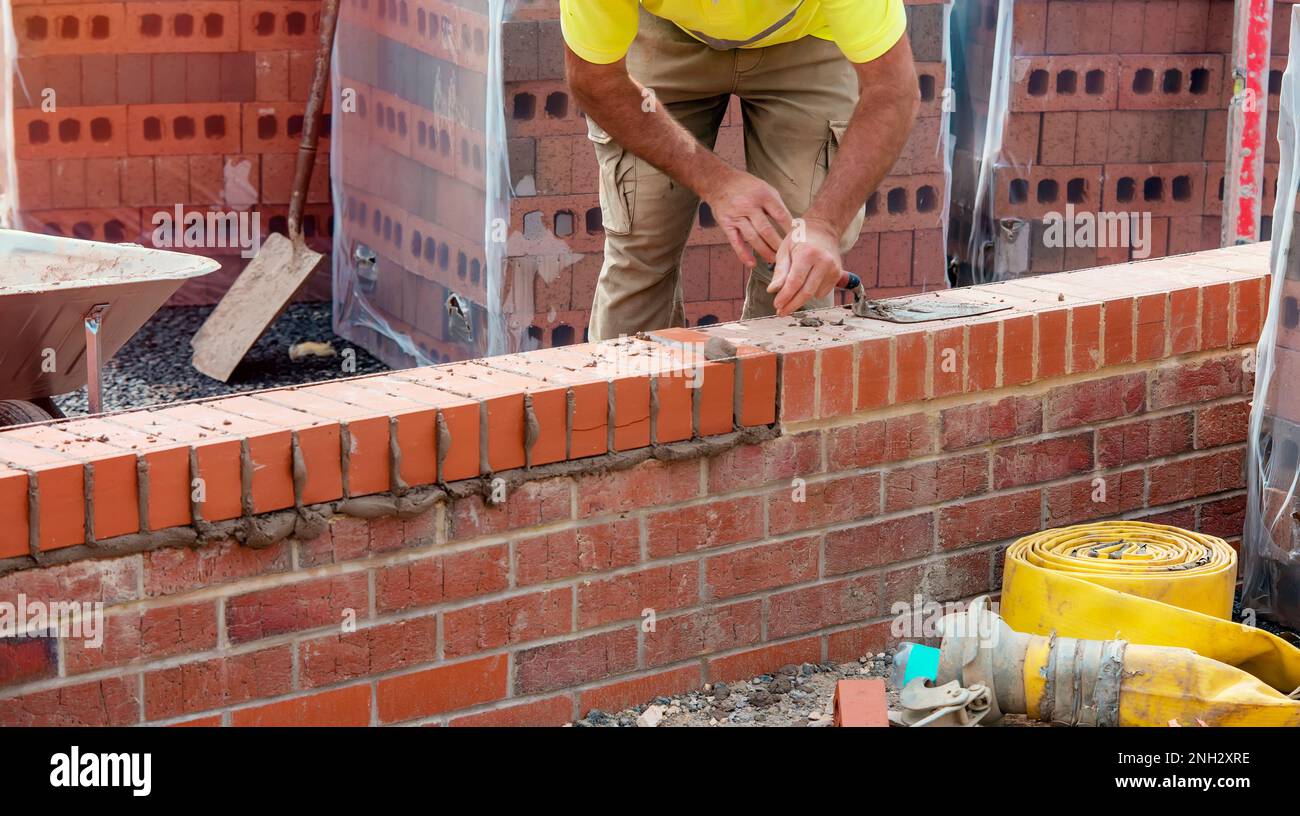 Industrial bricklayer laying bricks on cement mix on construction site