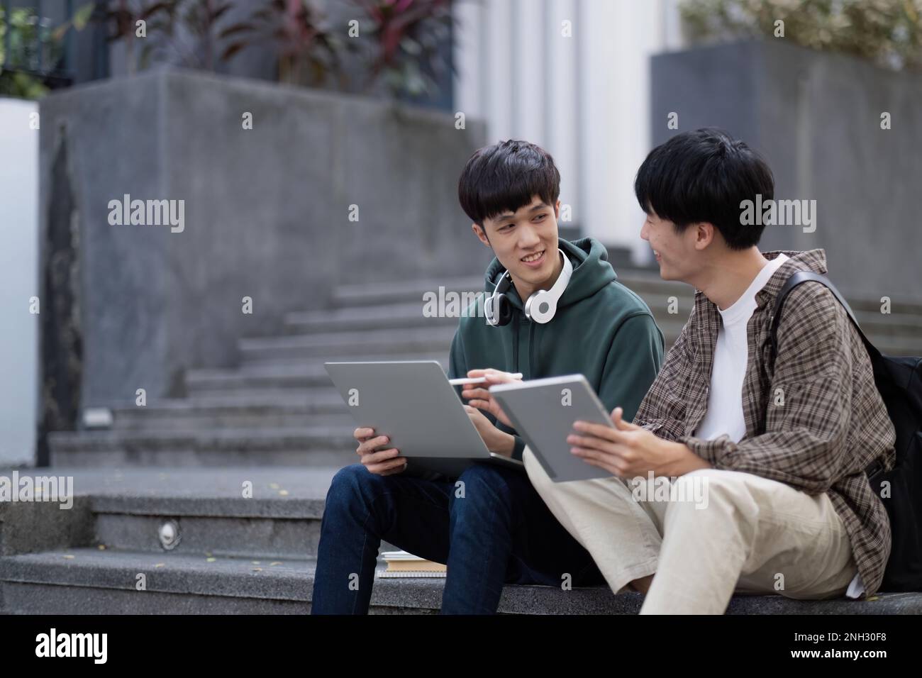 Two young Asian male college students discussing and working on their ...