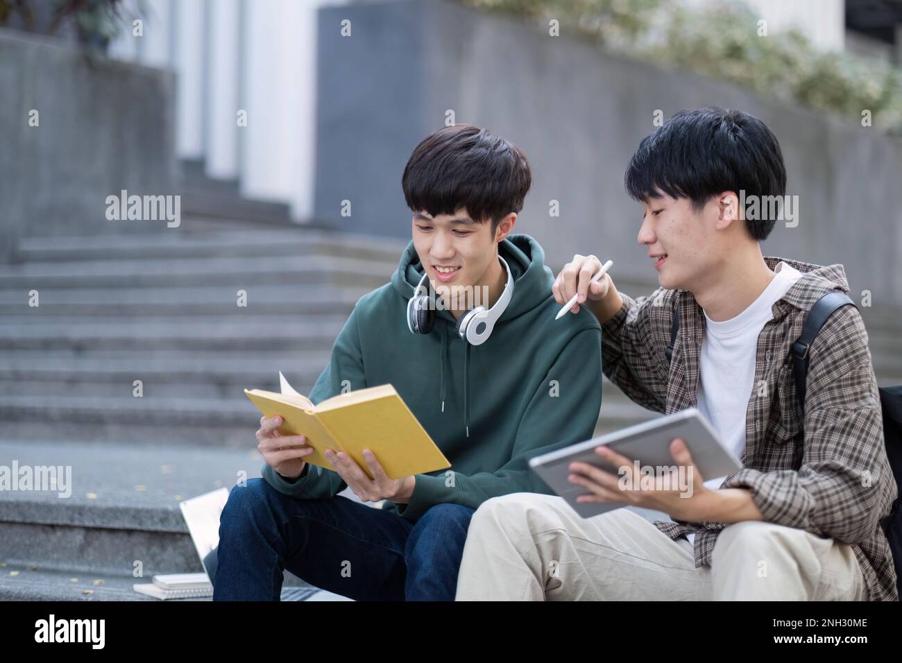 Two young Asian male college students discussing and working on their ...