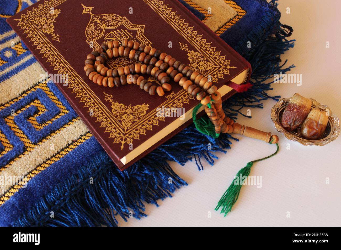 Holy quran and prayer rosary on prayer mat on white background. date