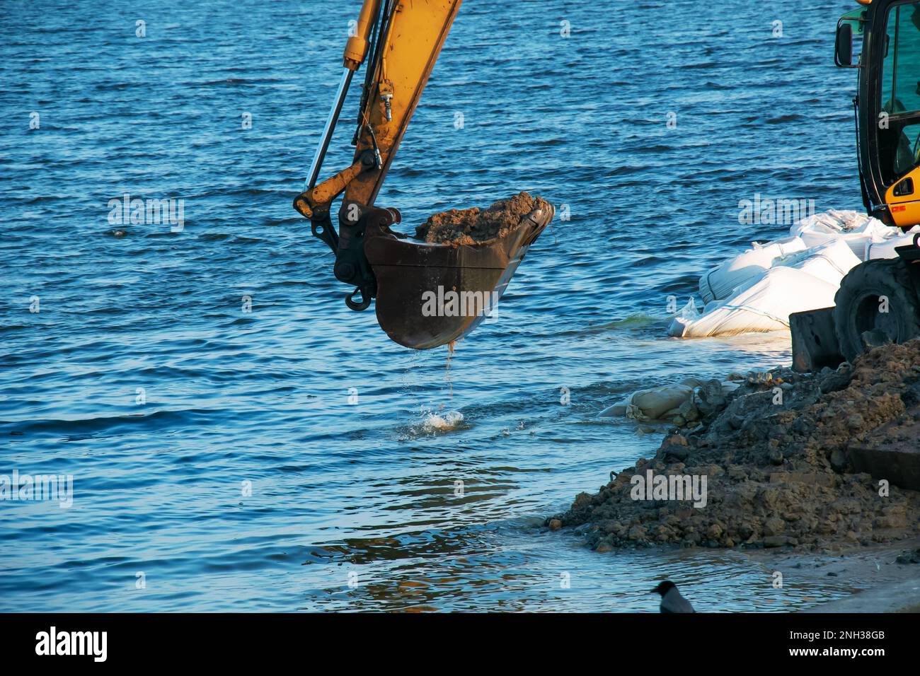 Excavator works to strengthen the embankment. Hydraulic excavator working on the river bank