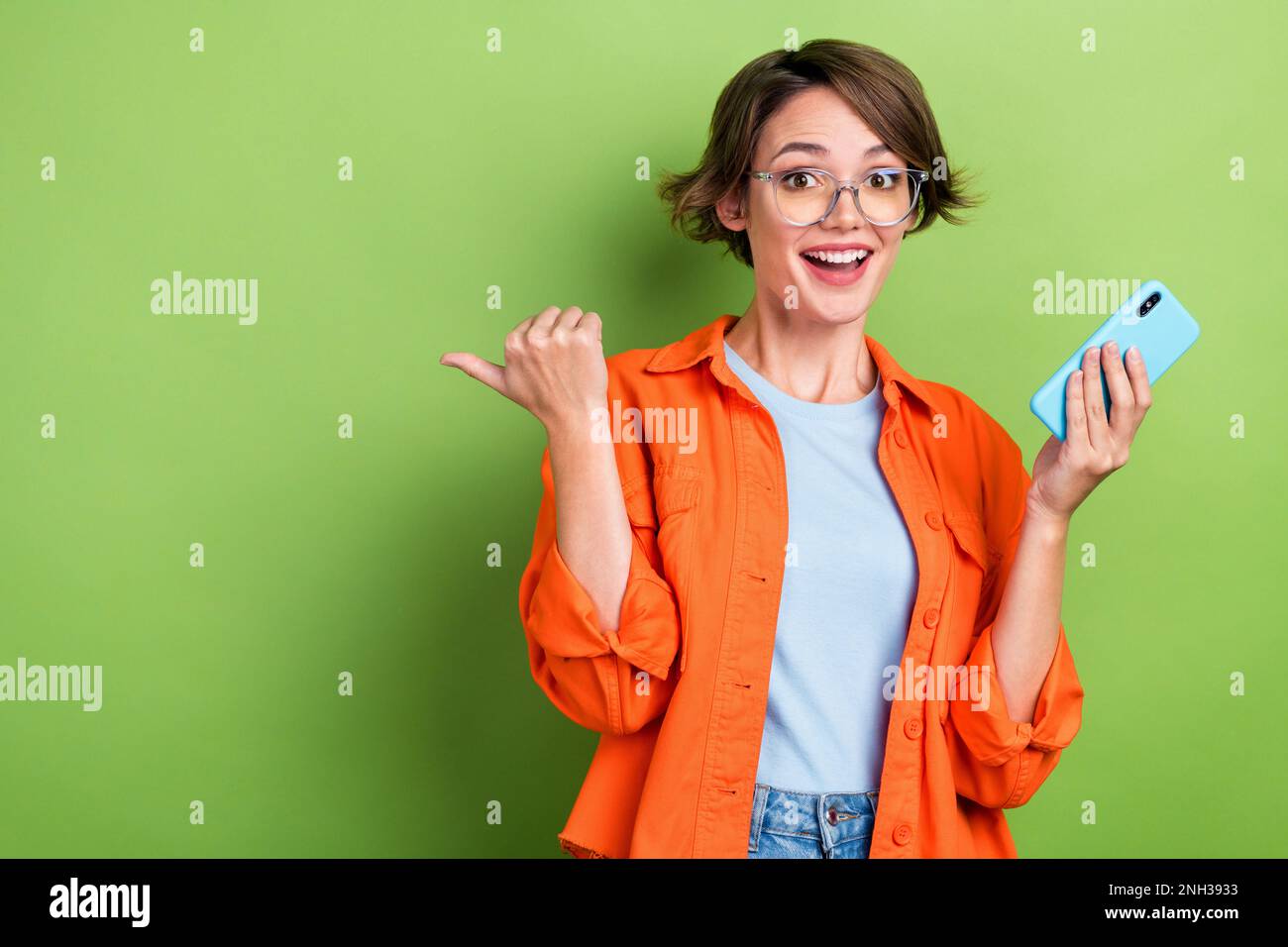 Photo of sweet impressed woman wear denim jacket spectacles typing modern device thumb empty space isolated green color background Stock Photo