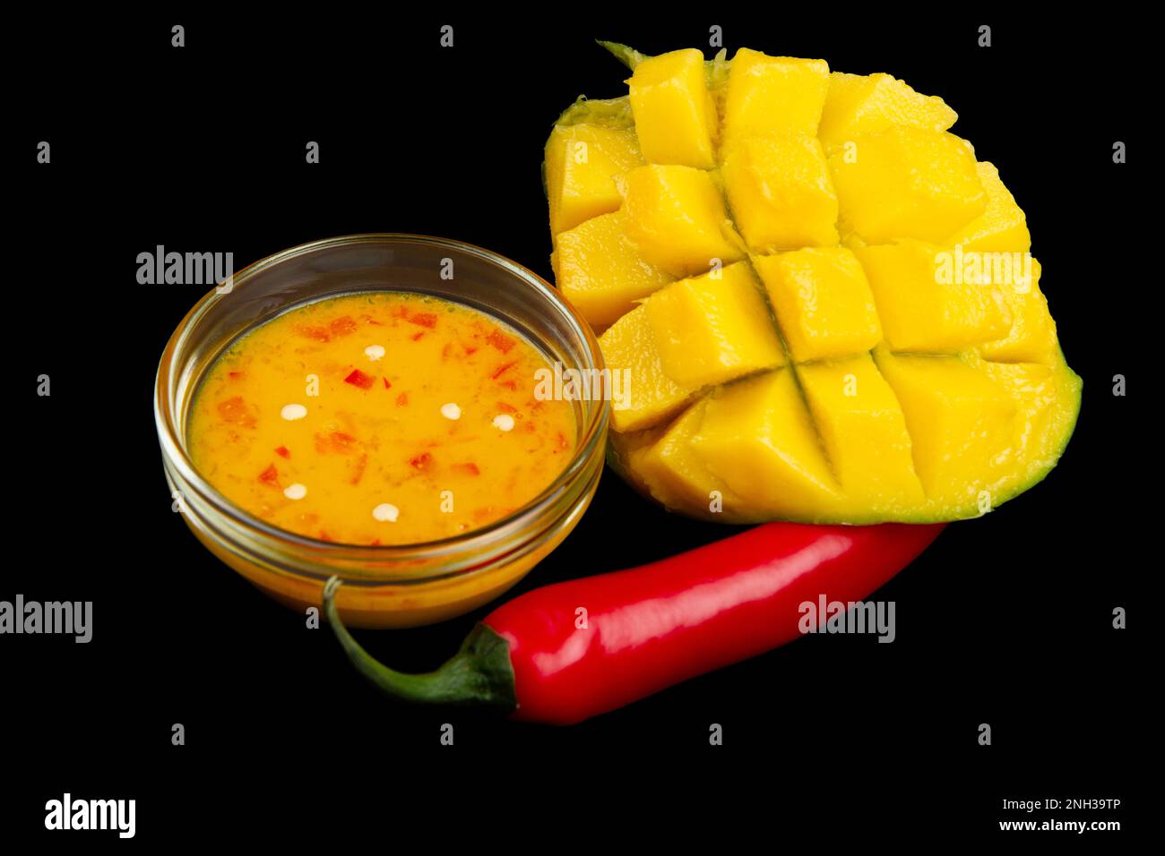 Cutted mango, chili pepper and mango chili sauce isolated on black background. Soft focus Stock Photo