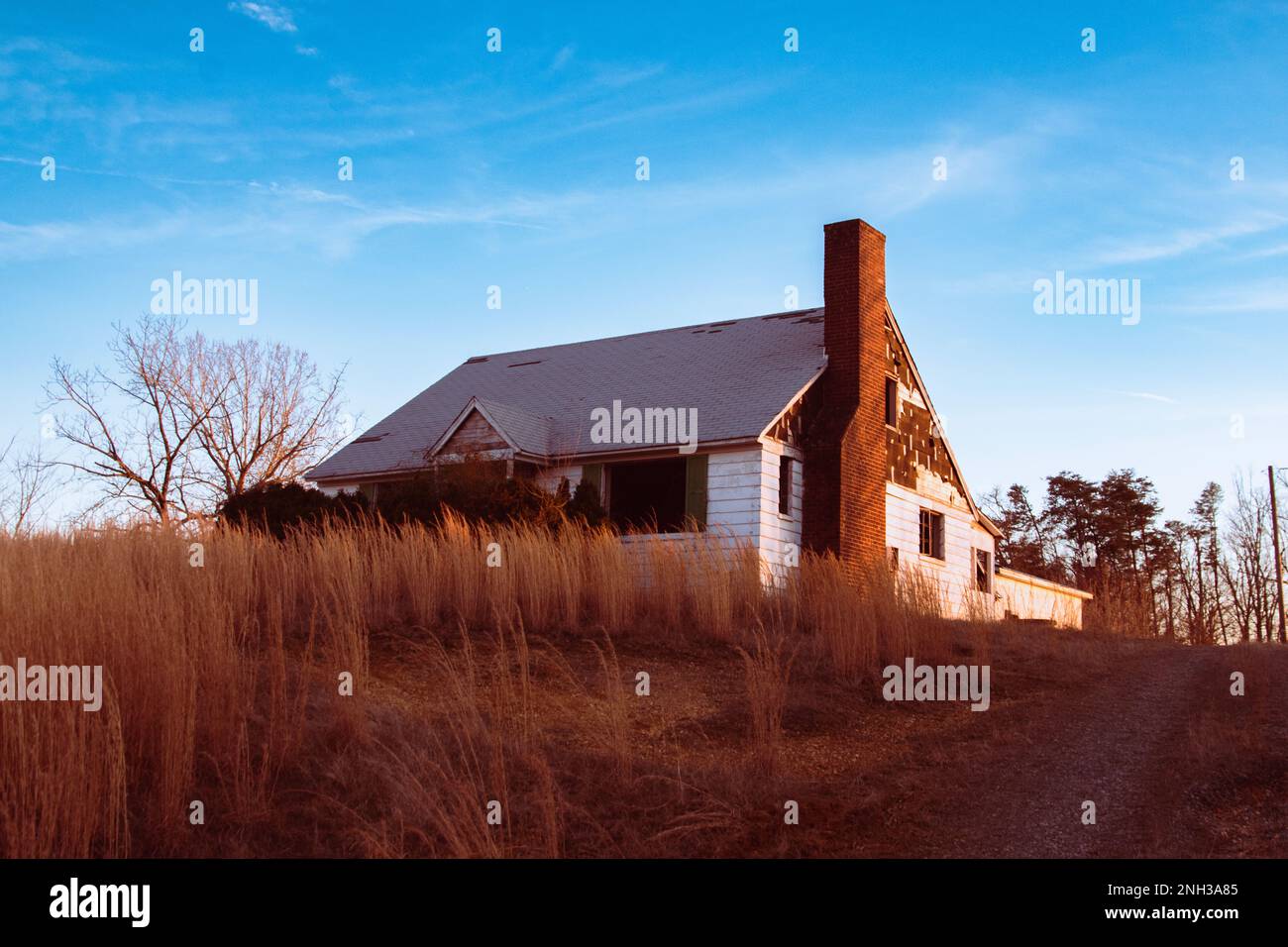 Rundown abandoned house, glowing in the evening sunlight. Stock Photo