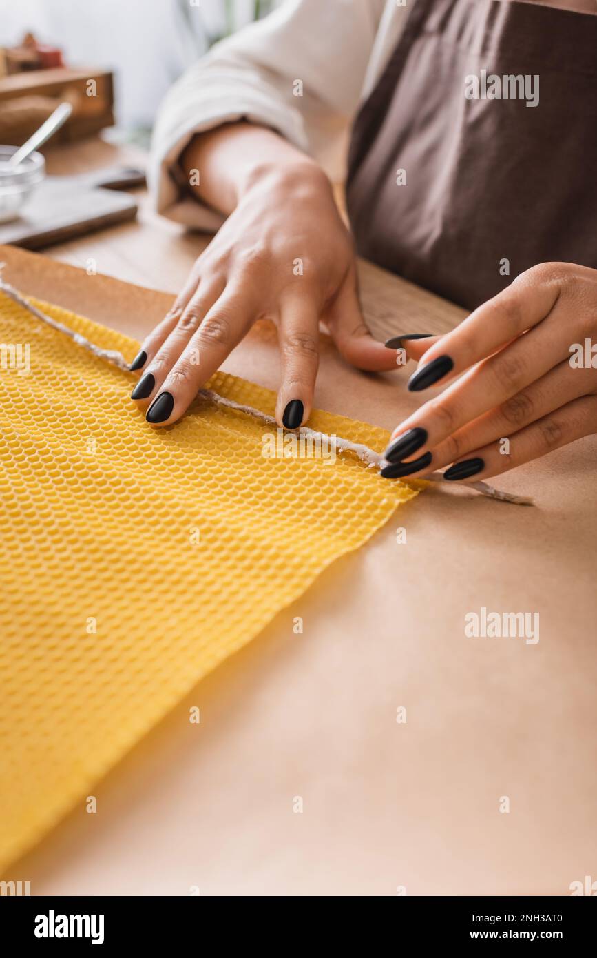 cropped view of african american craftswoman holding rope near wax sheet while making candle in workshop,stock image Stock Photo