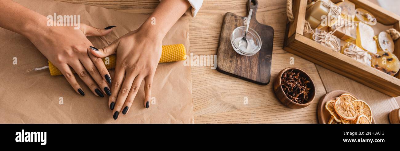 top view of cropped african american woman making natural candle on parchment near handmade soap, banner,stock image Stock Photo