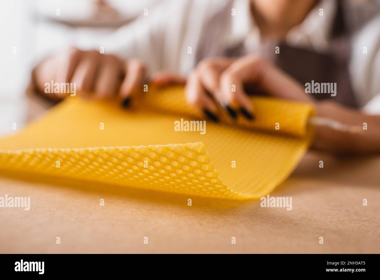 partial view of african american craftswoman rolling natural wax sheet on blurred background,stock image Stock Photo