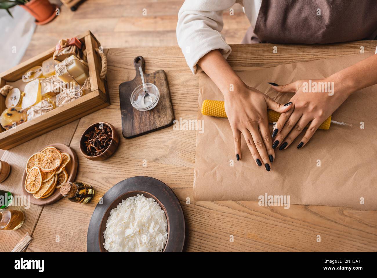 top view of cropped african american craftswoman making candle near soap bars and natural ingredients on wooden table,stock image Stock Photo