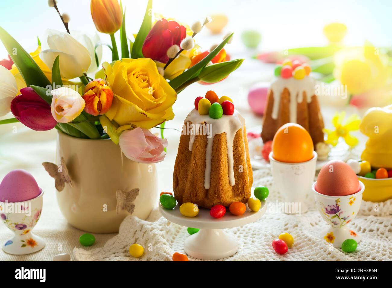 Easter table setting with spring flowers, cakes and easter eggs. Stock Photo