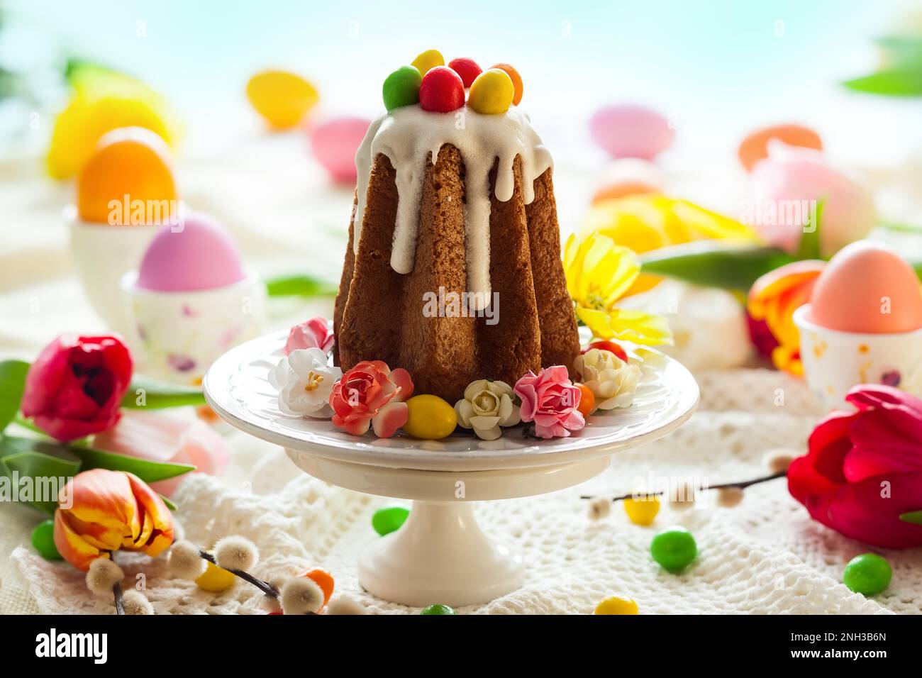 Easter table setting with spring flowers, cakes and easter eggs. Stock Photo