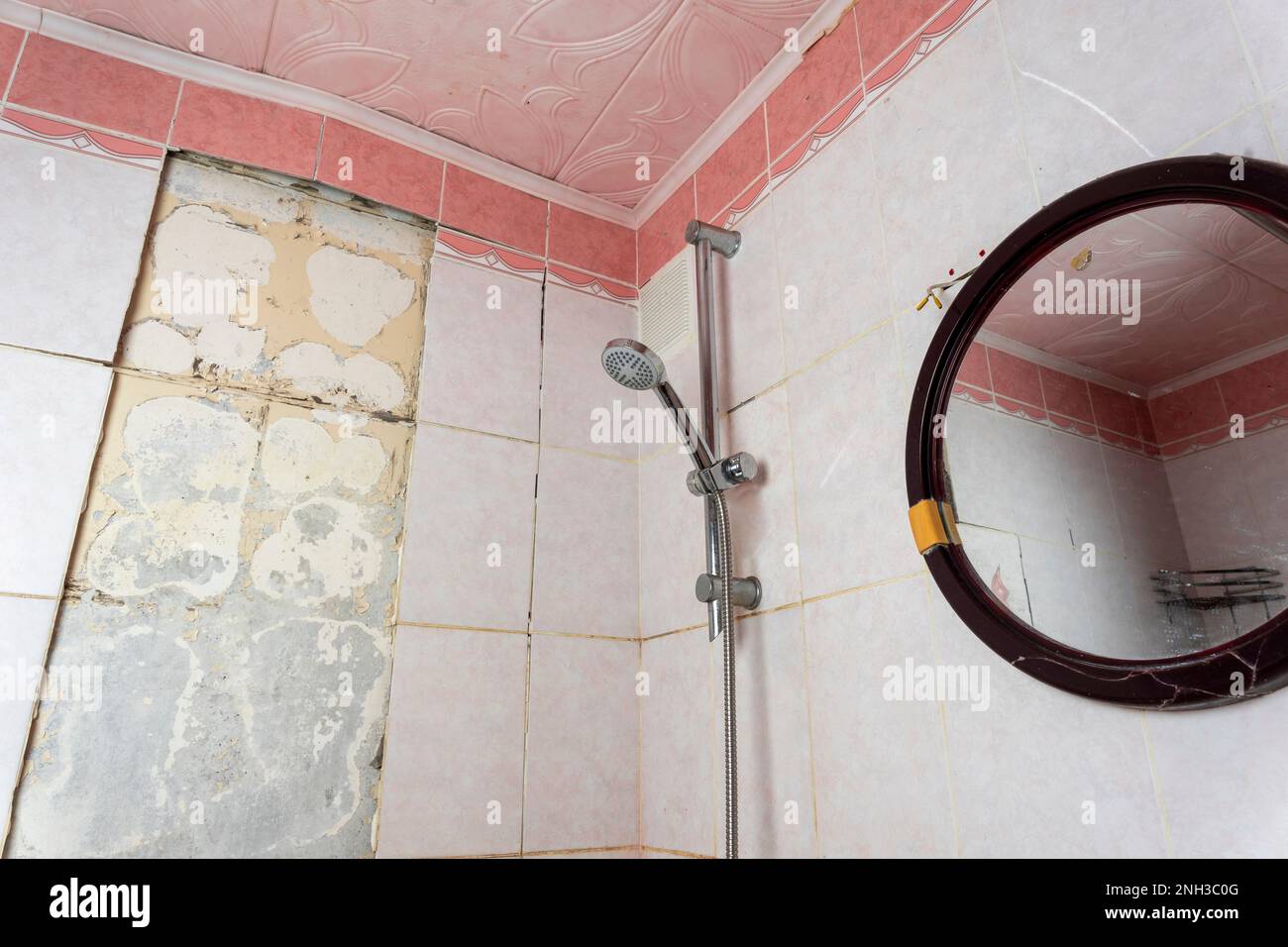 old dirty shabby bathroom with fallen tiles. old shelf. shower stand Stock Photo