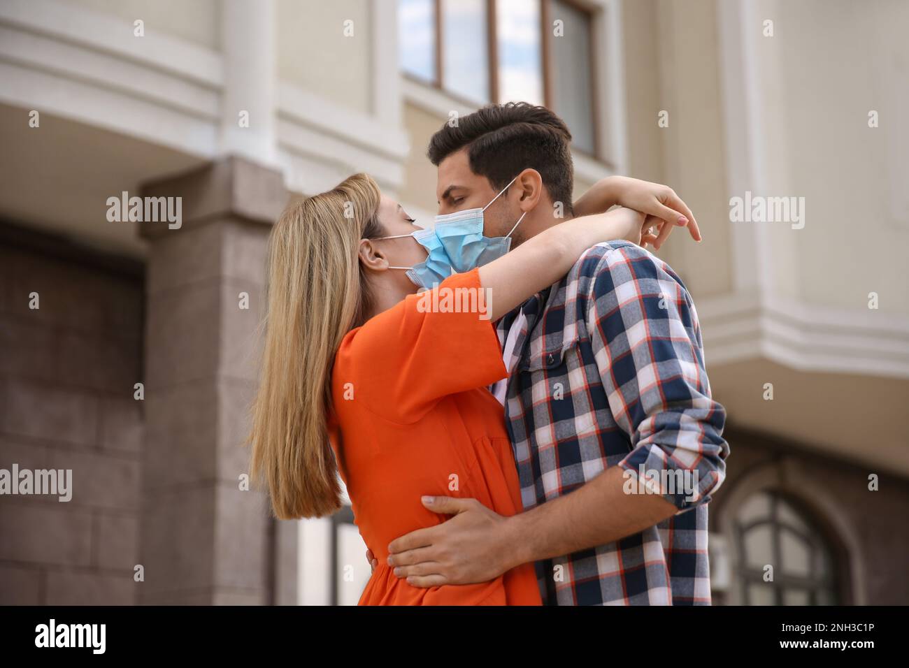 Couple in medical masks trying to kiss outdoors Stock Photo - Alamy