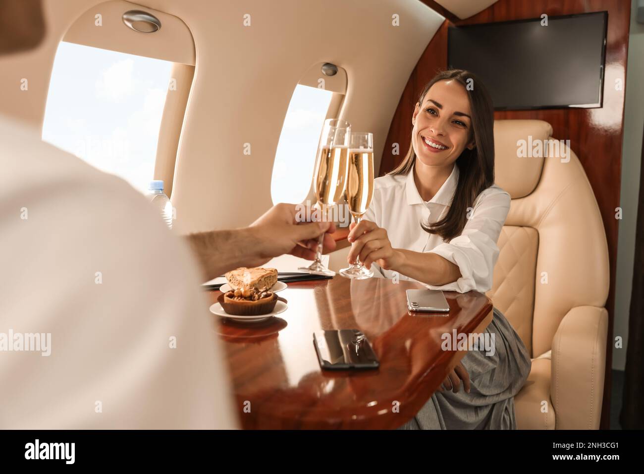 Colleagues clinking glasses of champagne at table in airplane during