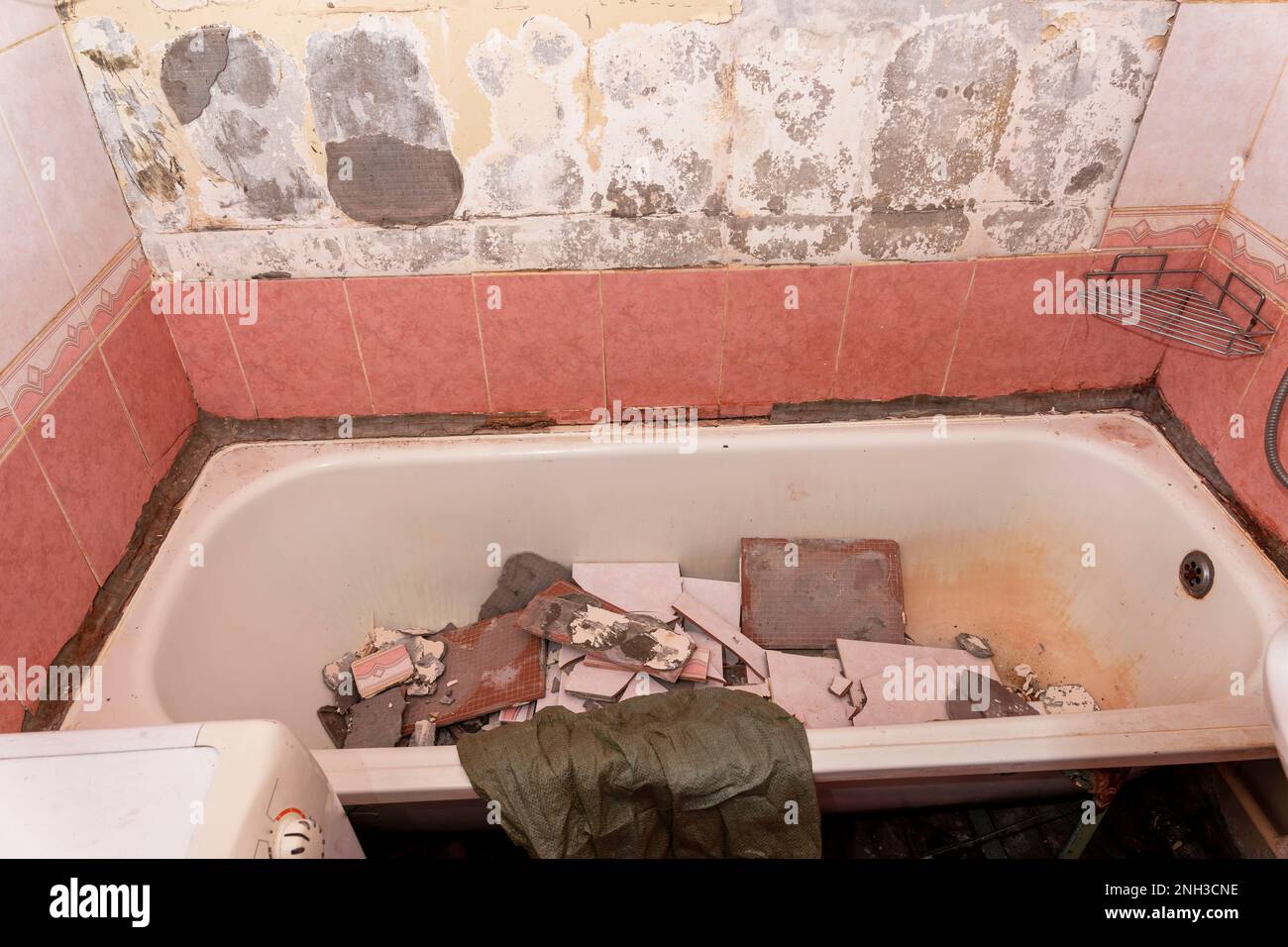 an old dirty shabby bathroom with fallen tiles. repair Stock Photo