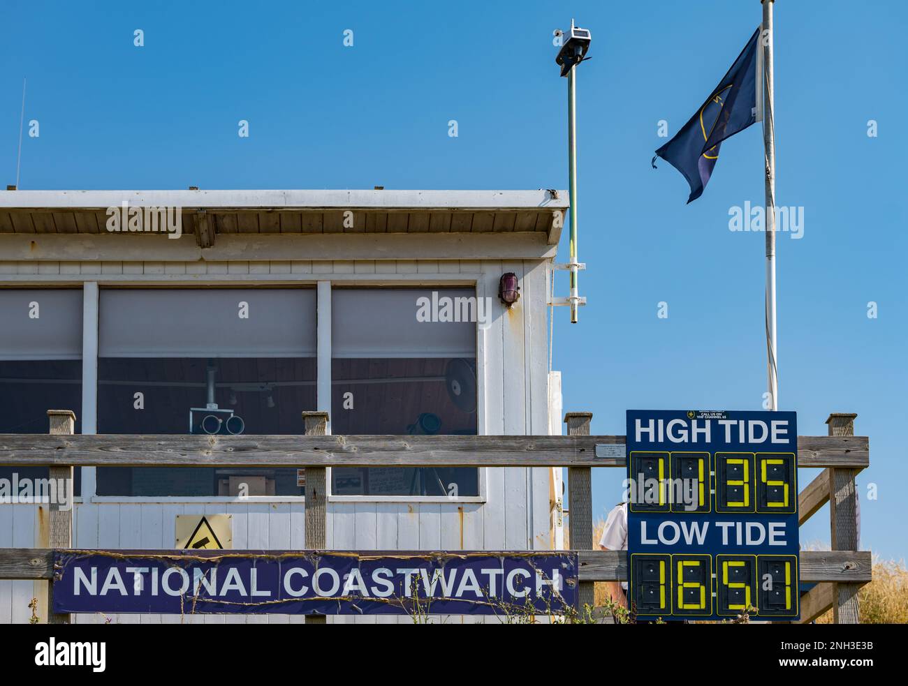 National Coastwatch or Coastguard monitoring hut with tide times, Hive Beach, Burton Bradstock, Dorset, England, UK Stock Photo
