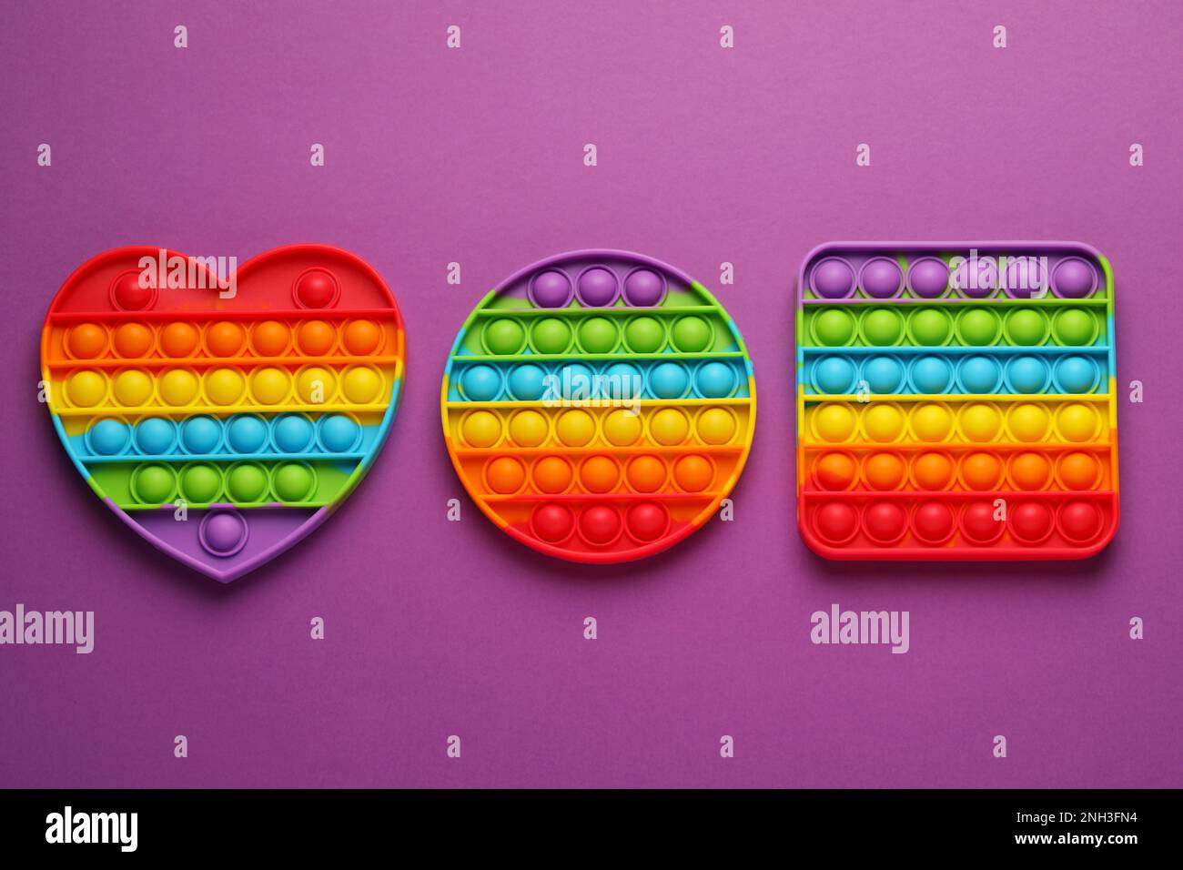 Rainbow Pop It Fidget Toys On Purple Background Flat Lay Stock Photo rainbow-pop-it-fidget-toys-on-purple-background-flat-lay-stock-photo
