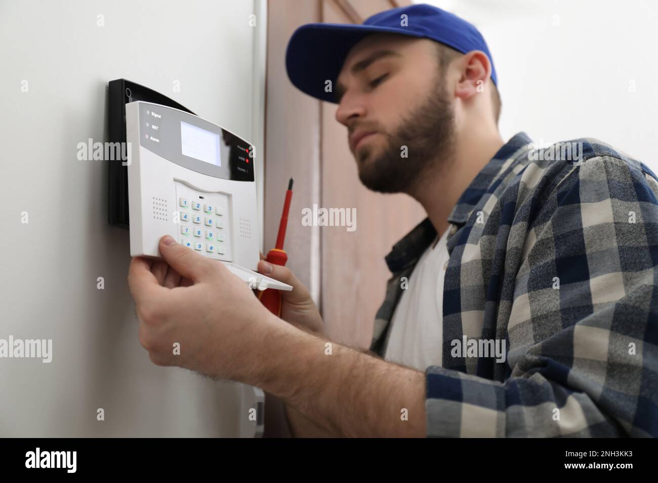 Man installing home security system on white wall in room Stock Photo