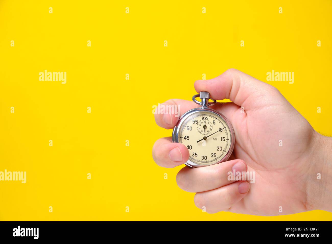 Stopwatch in hand yellow background Stock Photo Alamy
