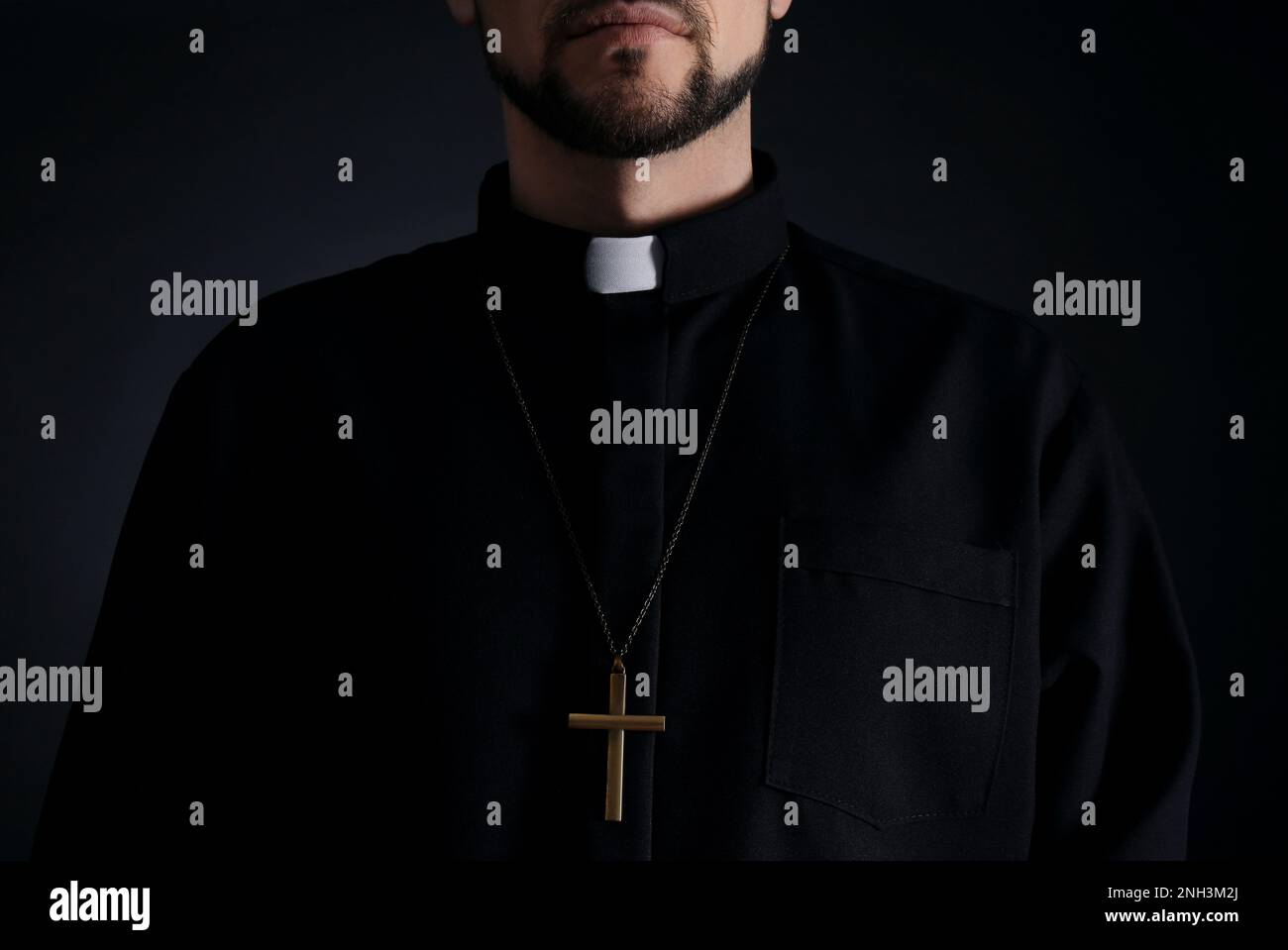 Priest wearing cassock with clerical collar on dark background, closeup Stock Photo