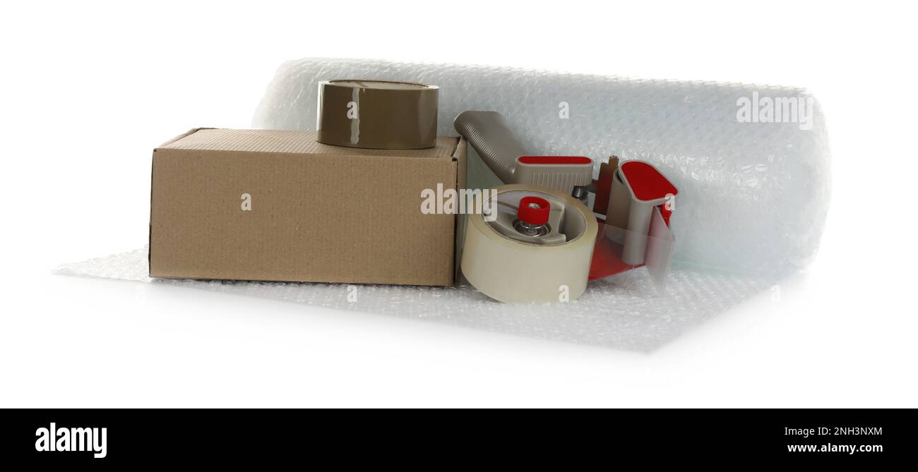 Bubble wrap roll, cardboard box and tape dispenser on white background