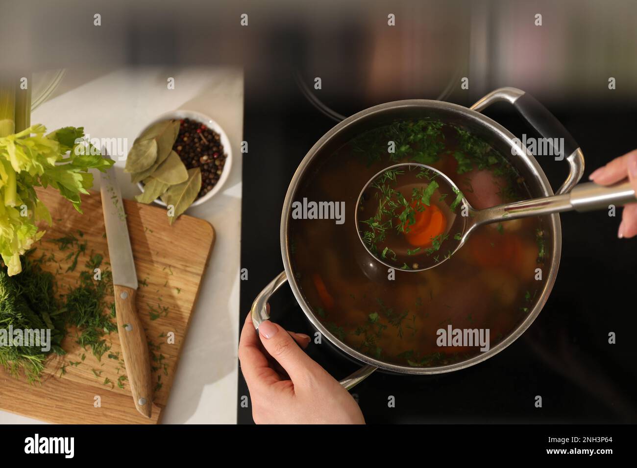 Woman making bouillon on stove, top view. Homemade recipe Stock Photo