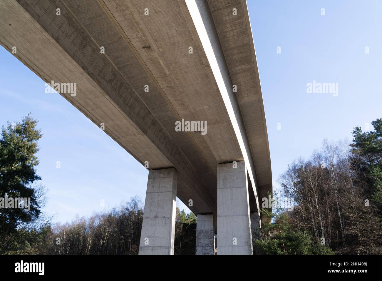 Big concrete highway bridge from below with blue sky on a sunny day in spring Stock Photo