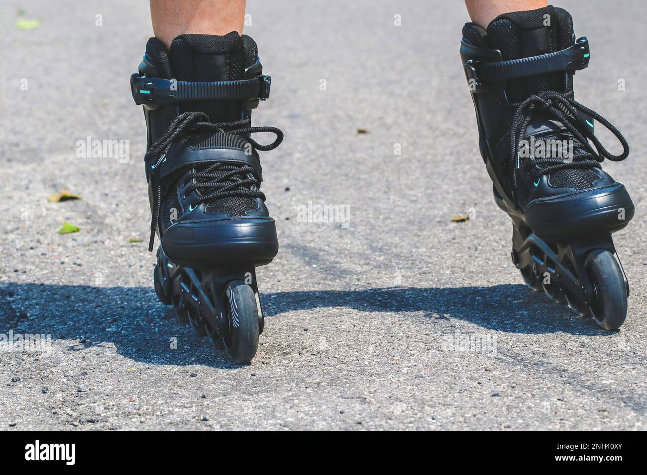Legs of woman who is learning of inline skating on asphalt road Stock