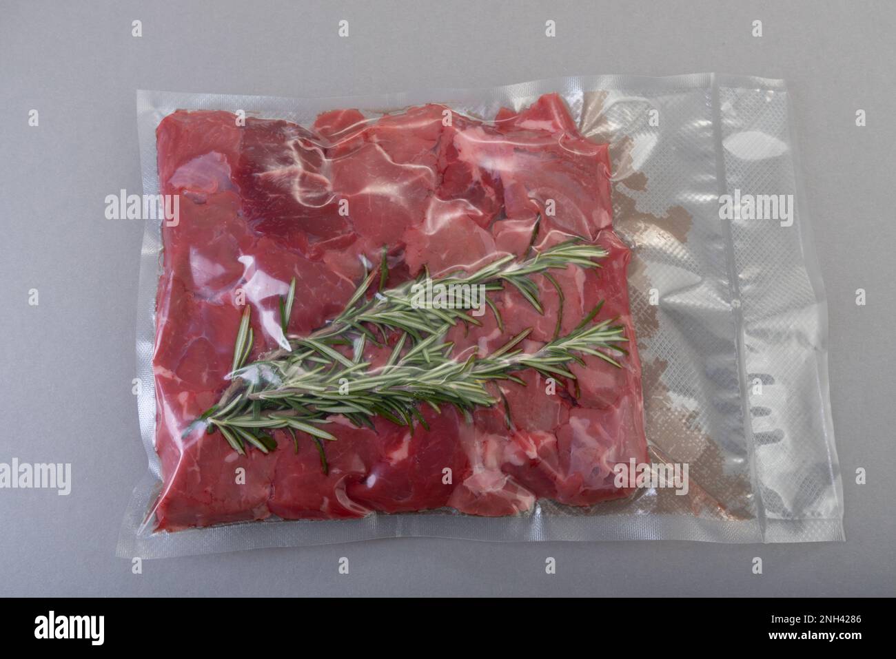 Raw beef diced for stew with rosemary sprig in vacuumsealed package