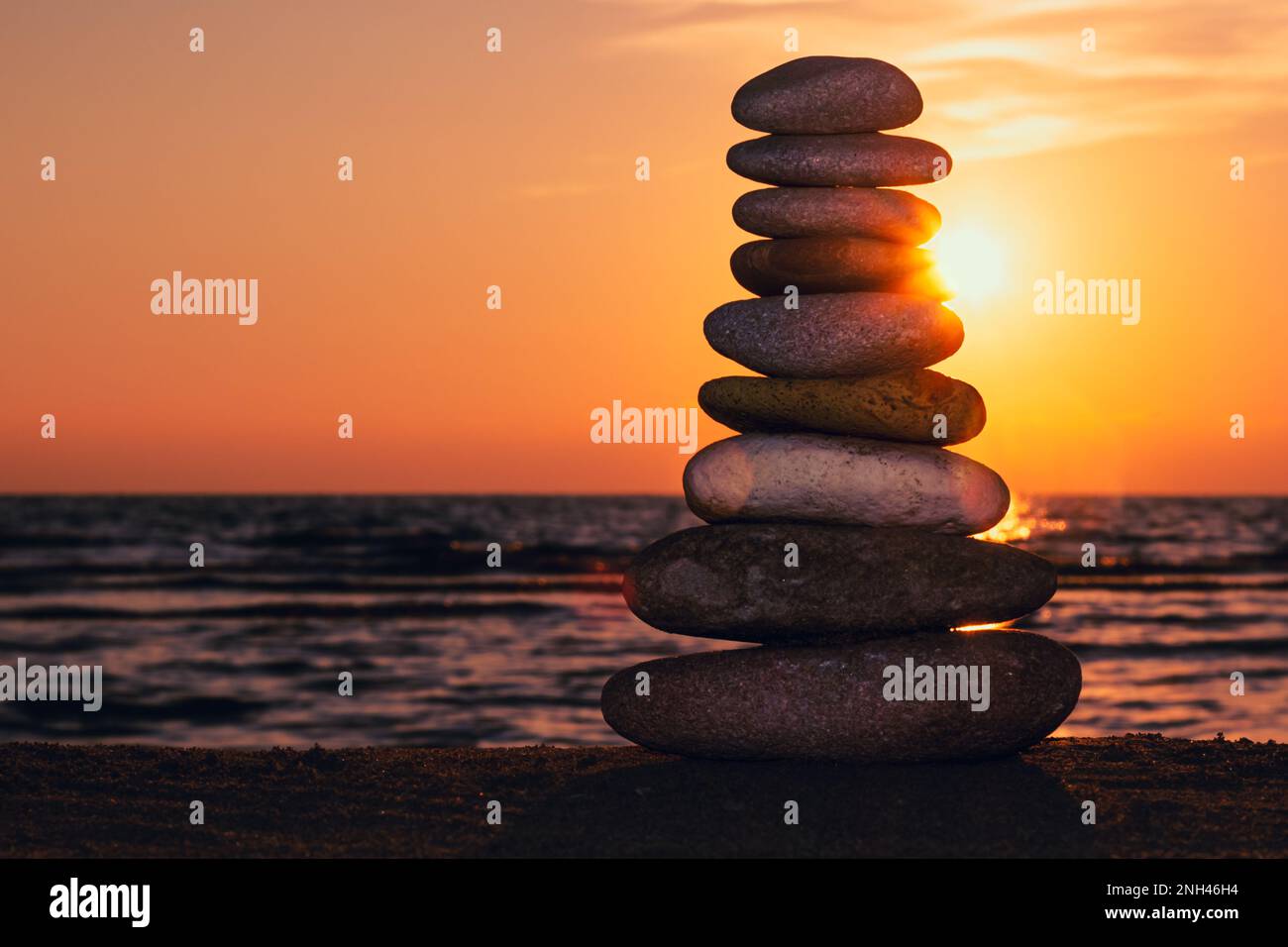 Stacked rocks on the beach with a sunset ocean in the background, Zen