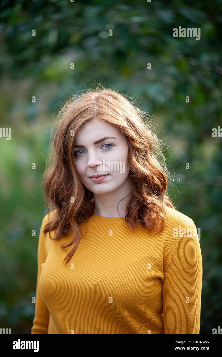 A redheaded woman wearing a mustard coloured jumper outside Stock Photo